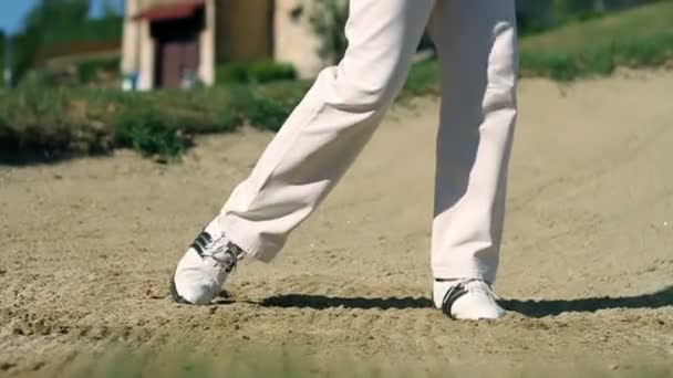 Tiro de un hombre golfista en un campo de golf de arena golpeando la pelota de golf blanco — Vídeos de Stock