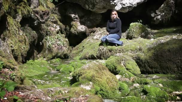 Bild på kvinna som sitter på klipporna täckt av mossa — Stockvideo