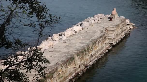 Tiro del muelle hecho de piedra con una estatua oscilante al final de ella — Vídeos de Stock