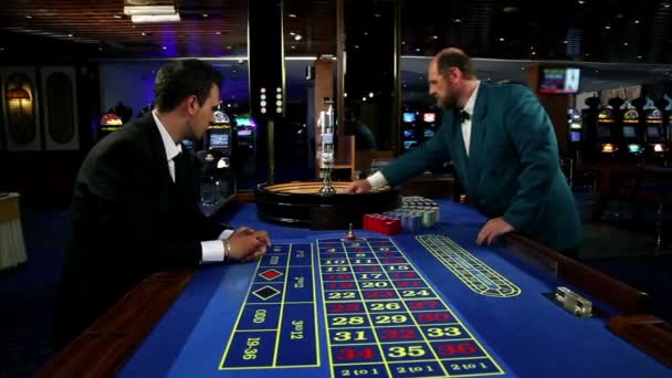 Jonge en aantrekkelijke man spelen roulette in casino — Stockvideo