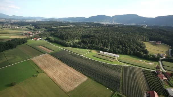 Vue panoramique depuis un hélicoptère représentant une vallée avec des champs, des prairies, une forêt et peu de maisons 