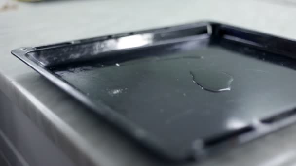 Close up shot of a black baking sheet that man is greasing with olive oil — Stock Video