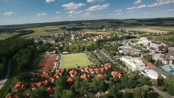 Scivolo panoramico girato da elicottero che rappresenta una valle popolata da alcune case e laghetto sul lato destro di questo paesaggio — Video Stock