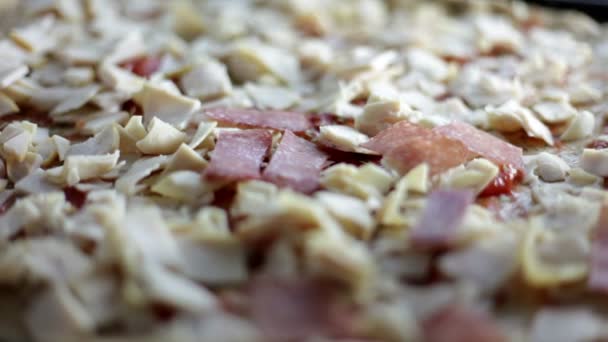 Nahaufnahme eines schwarzen Backblechs mit Teig und einer Person, die verschiedene Zutaten für Pizza anlegt — Stockvideo