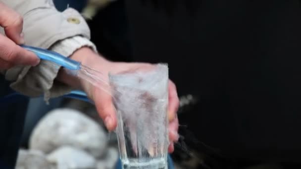 Shot van de stromende water van een man in het glas — Stockvideo