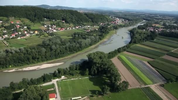 Панорамний слайд, знятий з вертольота, що представляє русло річки, який повільно проходить через красиву зелену долину з невеликими селами біля річки — стокове відео