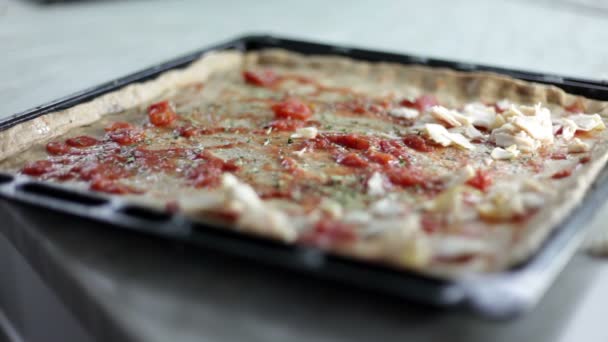 Close-up shot van een zwart blad met deeg en een persoon die op verschillende soorten ingrediënten voor pizza zet bakken — Stockvideo