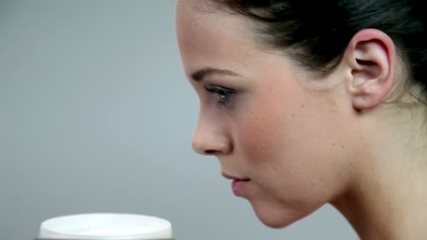 Молодая женщина нюхает крем для тела, богатый витаминами — стоковое видео