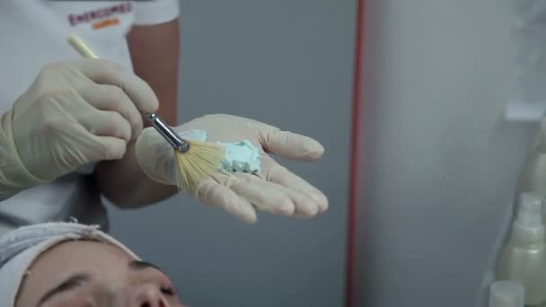 Kosmetikerin trägt Maske auf das Gesicht der Kundin auf — Stockvideo