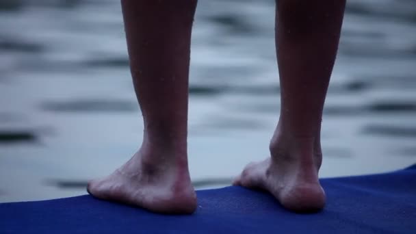 Молодой человек стоит на базе, прыгает в озеро — стоковое видео