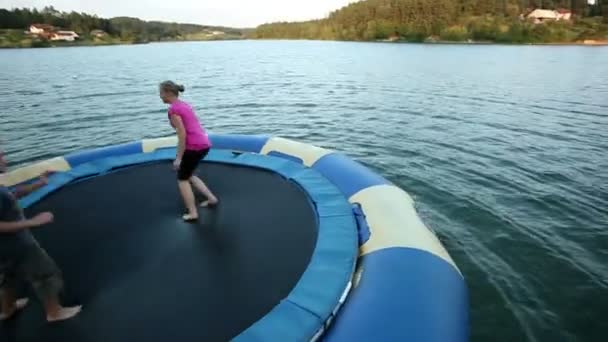 People jumping on trampoline in water — Stock Video