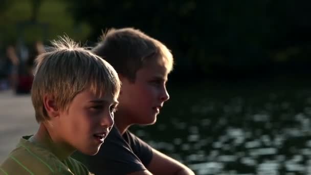 Jonge jongens kijken naar het meer en praten — Stockvideo