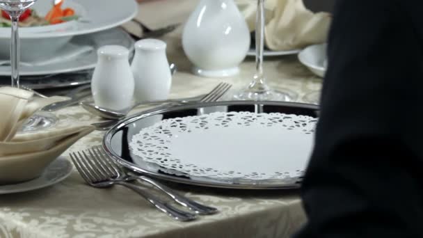 Decorative place setting for romantic dinner and waiter who brings young man delicious starter — Stock Video