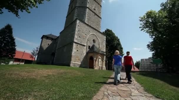 Jonge mensen een bezoek aan parochiekerk op zonnige dag — Stockvideo