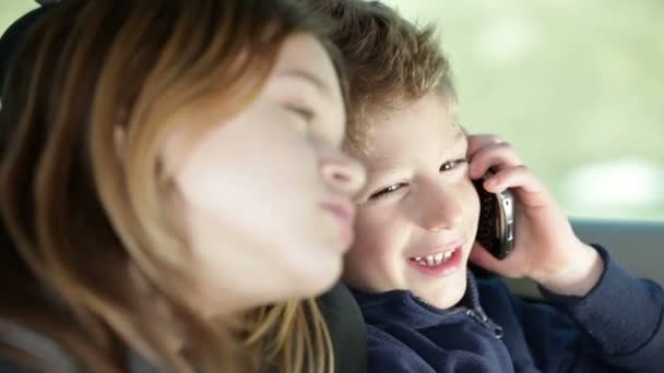 Barn i bilen spelar med mobiltelefon medan familjen reser till plats — Stockvideo