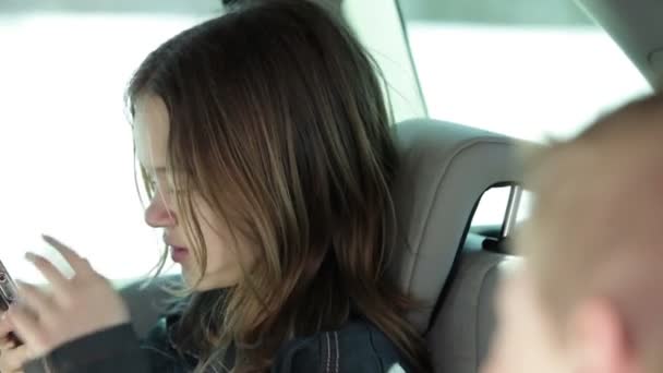 Ältere Schwester auf dem Rücksitz des Autos am Telefon — Stockvideo