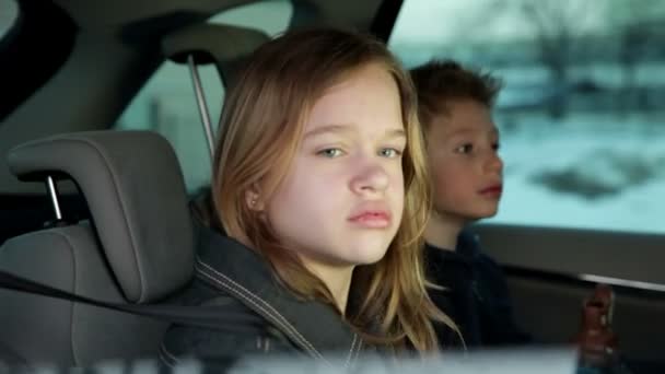 Hermano y hermana en el asiento trasero de un coche mientras la familia va de vacaciones — Vídeo de stock