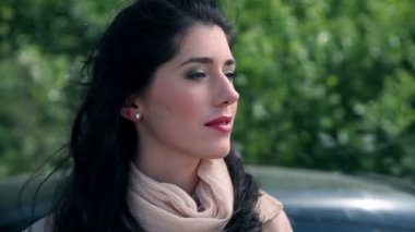 Arabanın yanında duran ve birine gülümseyen güzel kadın