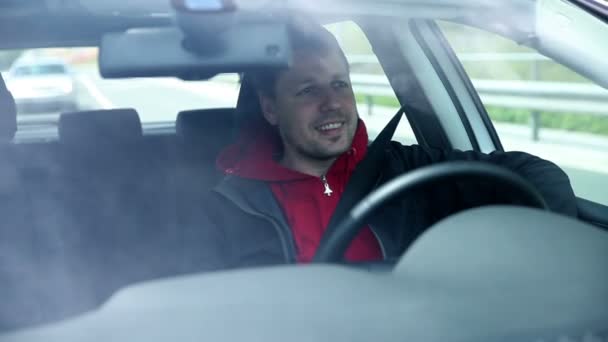 Hombre conduciendo sonriendo y saludando a los transeúntes — Vídeo de stock