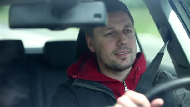 Hombre conduciendo coche y sonriendo a los transeúntes — Vídeo de stock