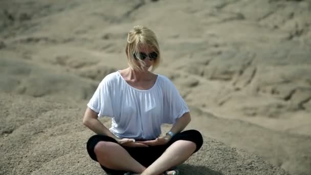 Jongere vrouw doet yoga op rotsachtige landschap van safari — Stockvideo