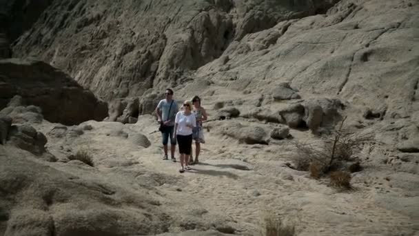 Tres turistas suben por el terreno rocoso en Safari — Vídeos de Stock