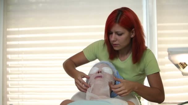 Средний снимок терапевта, добавляющего маску к коже лица — стоковое видео