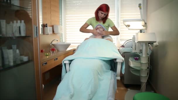 Voorzichtig toe te voegen massage crème op de huid van het gelaat — Stockvideo