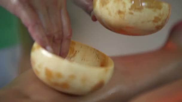 Gros plan de massage tapotant sur les jambes de la femme avec coque de noix de coco 