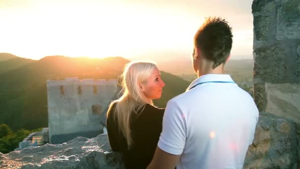 Pareja joven disfrutando de romántica vista del atardecer sobre una ciudad desde el castillo — Vídeo de stock