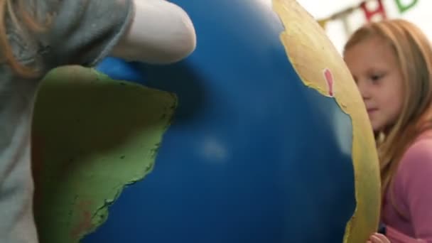 Lage hoek schot van kinderen spelen met earth globe — Stockvideo