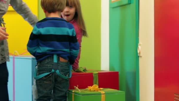 Kleine Kinder spielen im Kindergarten mit Geschenkboxen — Stockvideo