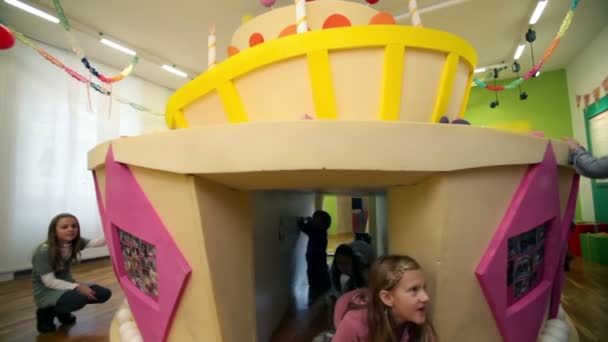 Giovani ragazzi e ragazze nella scuola materna che giocano con enorme torta di compleanno — Video Stock