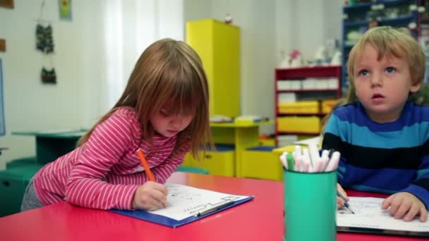 Дети в детском саду рисуют на бумаге — стоковое видео