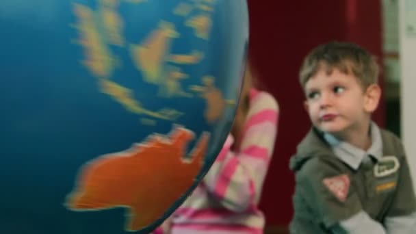Young boy turning around big Earth globe — Stock Video