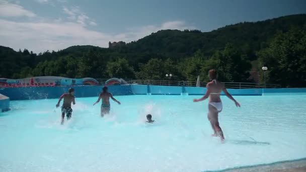 Grupo de jóvenes corriendo hacia la piscina divirtiéndose — Vídeo de stock