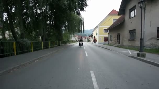 Низкий и более высокий угол съемки ретро мотоцикла проезжая по старому городу — стоковое видео