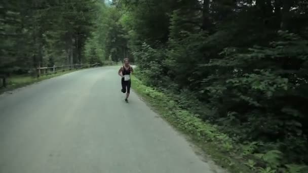 Seguimiento de la mujer corriendo por el camino forestal — Vídeos de Stock