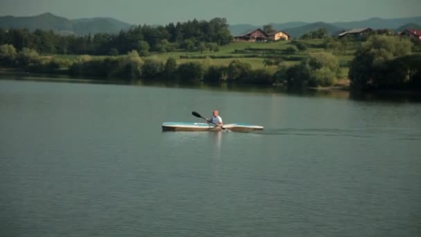 Bald man in big blue kayak on lake — Stock Video