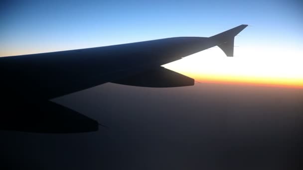 Gran ala de avión mientras vuela por encima de las nubes al amanecer — Vídeos de Stock