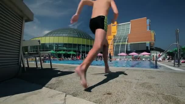 Menino pulando em piscina rastreamento guindaste tiro — Vídeo de Stock