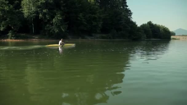 Weitschuss eines Mannes, der sehr schnell im See paddelt — Stockvideo