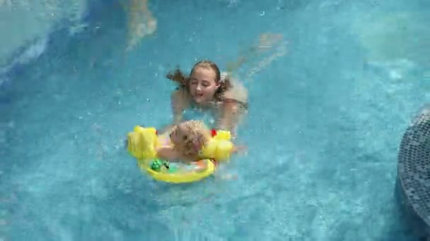 Chica y su hermano menor divirtiéndose en la piscina — Vídeo de stock