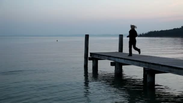 Vista panoramica sul mare mentre la donna fa jogging e si estende sul molo — Video Stock