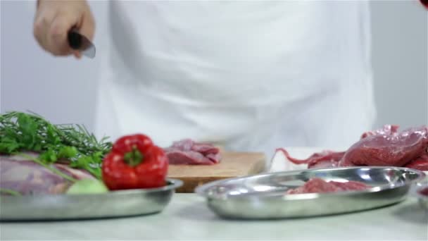 Metzger schneidet Rindfleisch mit Gemüse und rotem Fleisch auf den Tisch