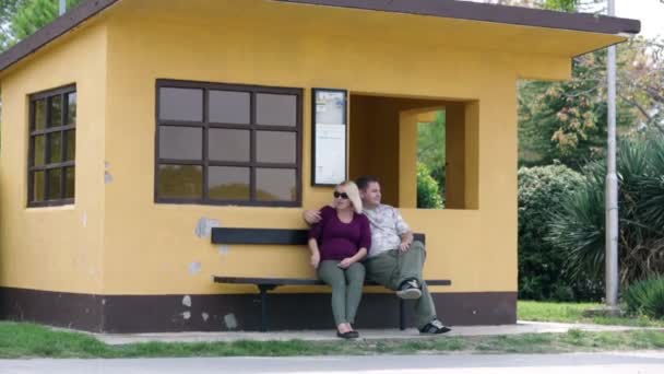 pár sedící na lavičce před domem oranžové