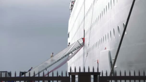 Disparo de personas que suben las escaleras para abordar en un crucero blanco hecho detrás de la valla — Vídeos de Stock