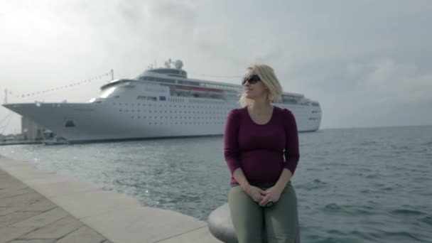 坐在码头上与巡洋舰在后面的女人 — 图库视频影像