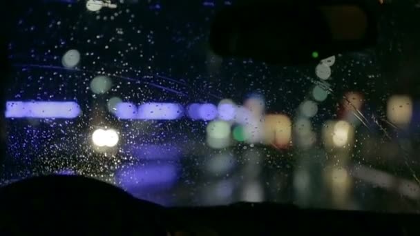 Unfocused shot through windshield in a city at night — Stock Video