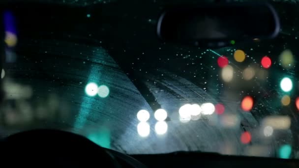 Дворники удаляют дождь, собранный на ветровом стекле во время ночной поездки по городу — стоковое видео